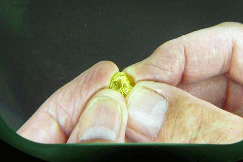 Estimation pièce de monnaie : la méthode du numismate, pas à pas 2 Petite pièce d'or tenue entre deux doigts, premier examen avant une estimation pièce de monnaie