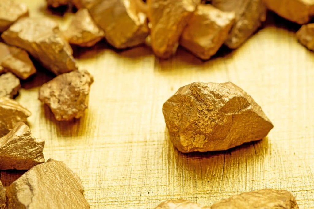 Comment investir dans l'or physique sans faux pas 3 Pépites d'or brutes posées sur une surface sombre